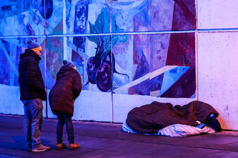 Volunteers Amy Herlich and Tom Marvit speak to a man sleeping on 23rd Street near Market Street. Volunteers spread out across the city to help the Office of Homeless Services conduct its winter point-in-time count of people living on the streets, Wednesday, January 24, 2024.