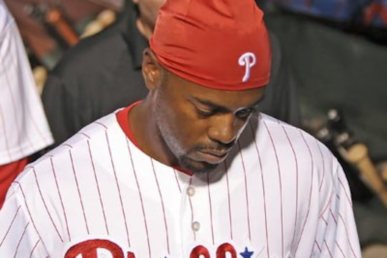 Shortstop Jimmy Rollins walks to the clubhouse with a trainer after re-injuring his calf. (Steven M. Falk / Staff Photographer)