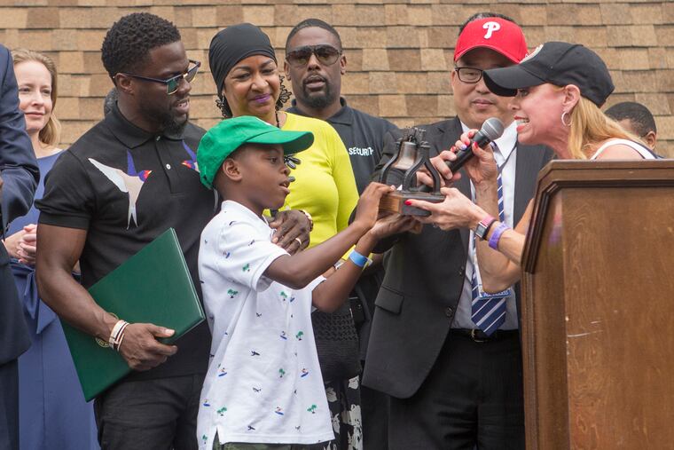 Kevin Hart, left, and his son, Hendrix, center, are presented with a Liberty Bell by City Representative Sheila Hess. Philadelphia marks Kevin Hart Day with a mural dedicated to the comedian on his 38th birthday last year. Hart will host the 2019 Academy Awards, fulfilling a lifelong dream for the actor-comedian.