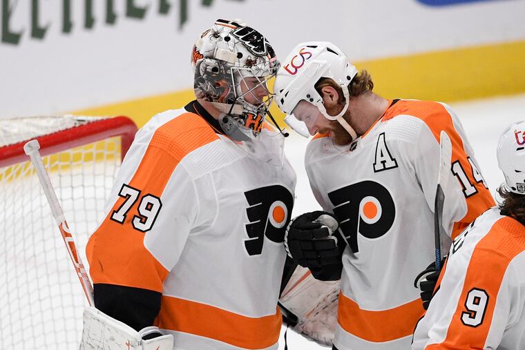 Flyers goaltender Carter Hart and center Sean Couturier react after the victory in Washington.
