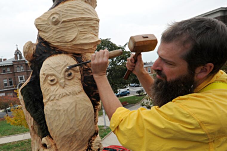 Wing uses a hammer and chisel to carve a detail. His sculpture will be formally unveiled Saturday. APRIL SAUL / Staff Photographer