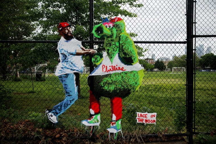 A yarnbomb from artist Nicole Nikolich, known as Lace in the Moon, adorns the chain-link fence at the corner of East Passyunk Avenue and Wharton Street in Philadelphia. The piece depicts the viral moment of Jason Kelce and the Phillie Phanatic jumping up and down in celebration from 2022.