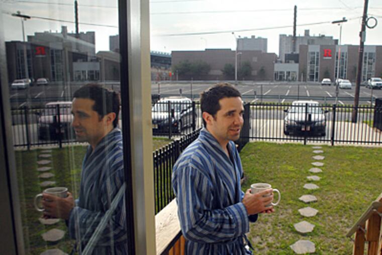 James Reilly stands at the back door of his home on North 2nd Street in Camden in July, the campus of Rutgers University - Camden in background. ( Tom Gralish / Staff Photographer )