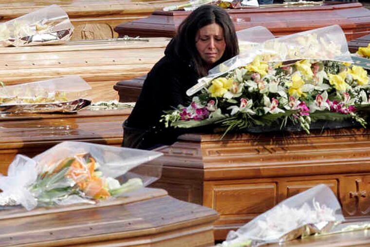 A woman kneels between coffins prior to the funerals yesterday for quake victims in L'Aquila, central Italy. At right, mourners pay their respects during the funeral service at the Guardia di Finanza Academy. Hours after the service, rescue crews began digging in the rubble of an apartment building after dogs found indications that people trapped inside might still be alive.
