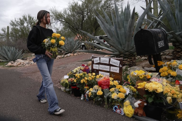 A person places flowers in front of Nancy Guthrie’s home in Tucson, Ariz., on Friday.