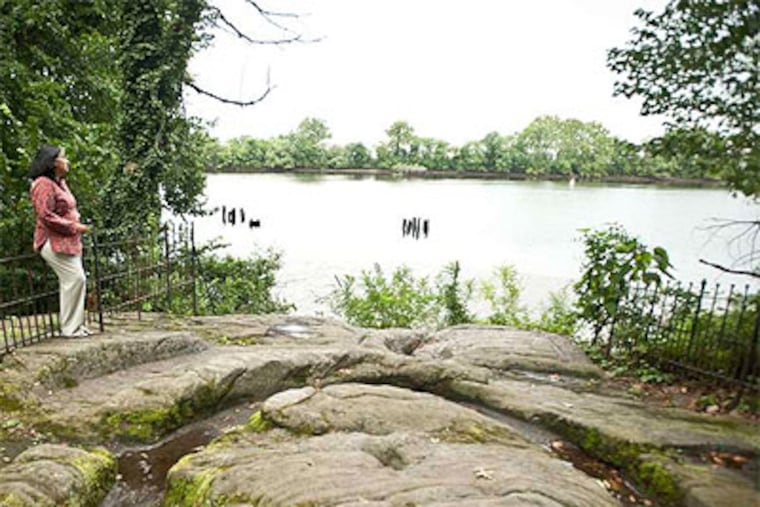 Maitreyi Roy, new executive director of Bartram's Garden in Southwest Philadelphia, stands on a large stone where the property meets the Schuylkill. (Ron Tarver / Staff Photographer)