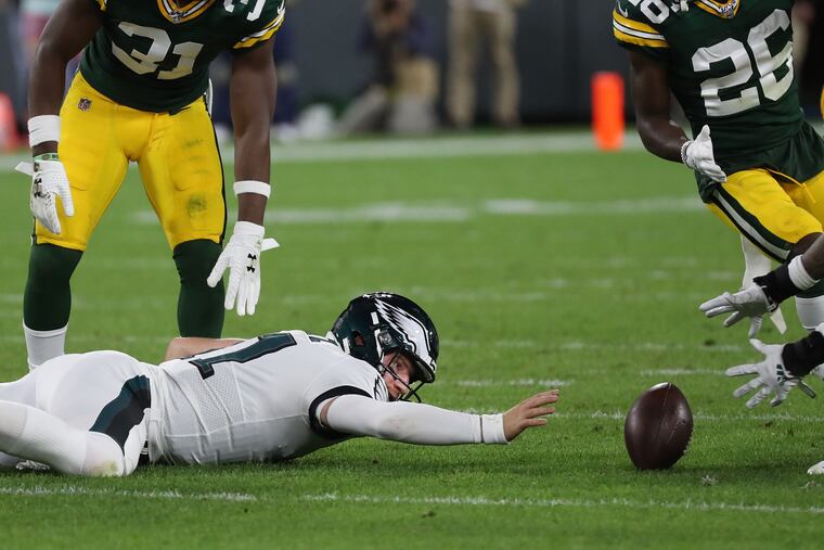 Carson Wentz (left) reaches for the ball as it rolls away from his grasp in the second quarter of Thursday’s game vs. Green Bay. He was ruled down by contact after a replay review.