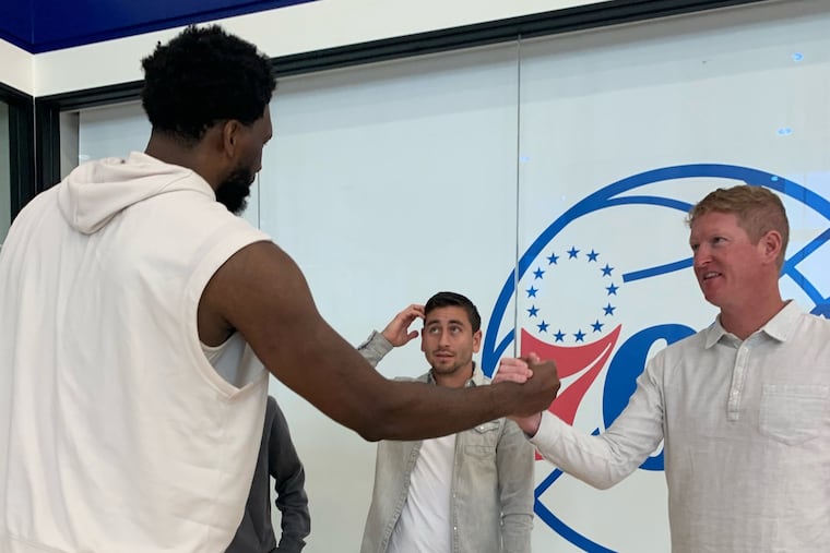Joel Embiid (left) shakes hands with Jim Curtin (right) as Alejandro Bedoya (center) looks on.