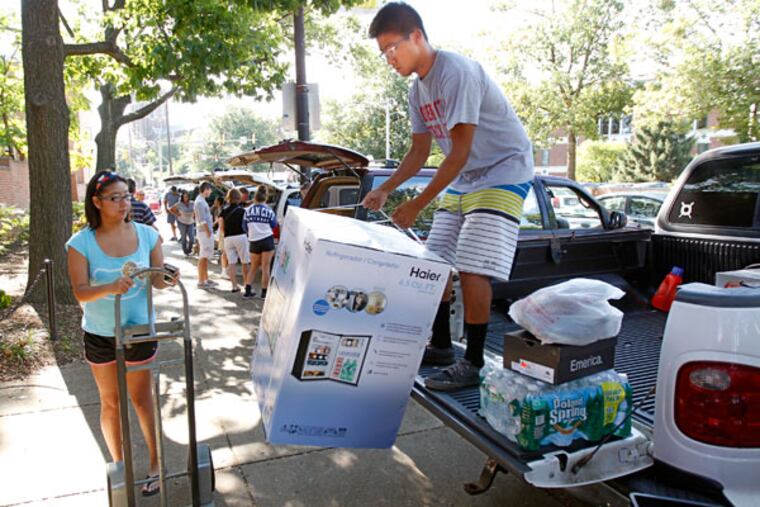 Eric Lam, a freshman at La Salle, unloads his dorm room refrigerator from the back of his truck while Andrienne Lam waits with the cart. (Michael Bryant/Staff Photographer)
