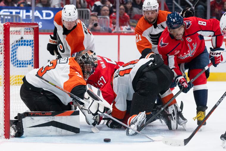 Flyers goaltender Samuel Ersson (33) watches the puck as Washington Capitals left wing Alex Ovechkin (8) reaches for it during the first period of their game on Friday in Washington.