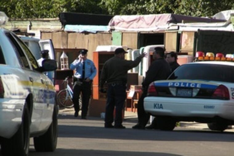 Police investigate the deaths of two men killed yesterday at an open-air market on West Indiana Avenue near Mutter Street. The area is well-known for its secondhand-goods merchants.