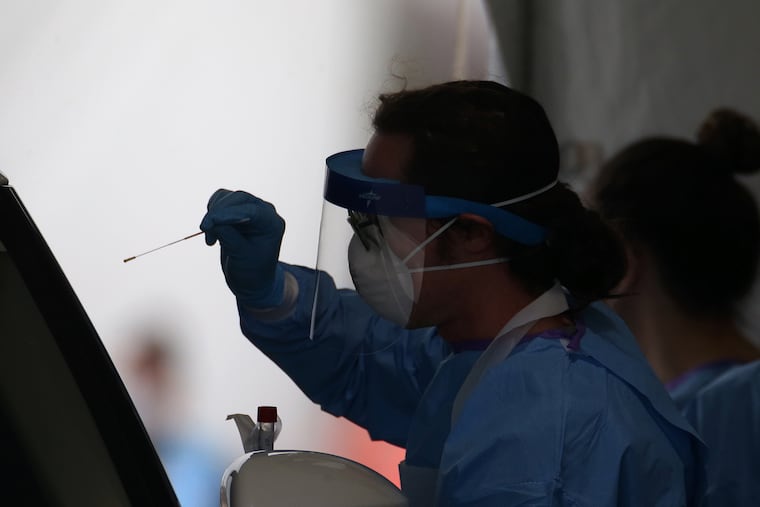 Stephen Bonett, a nurse and Philadelphia medical reserve corps volunteer, administers a nasal swab to a driver at the city's coronavirus testing site next to Citizens Bank Park in South Philadelphia earlier this month.