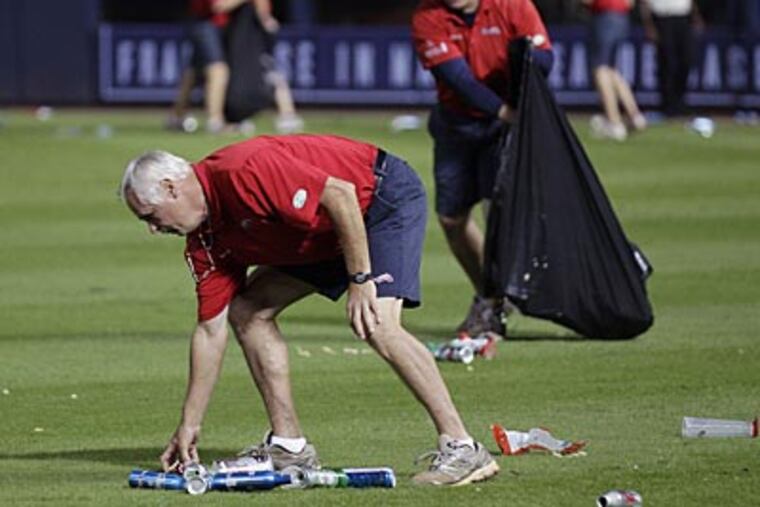 A Braves official picks trash up off the field during the eighth inning of the team's wild card game against the Cardinals. (AP)