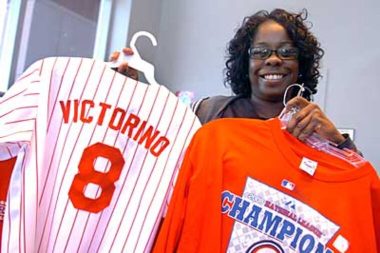 Cavetta Nesmith, 40, of West Oak Lane shows the merchandise she's buying today from the Majestic Clubhouse at Citizens Bank Park. Nesmith said she prays before every game. (Sarah J. Glover / Staff Photographer)