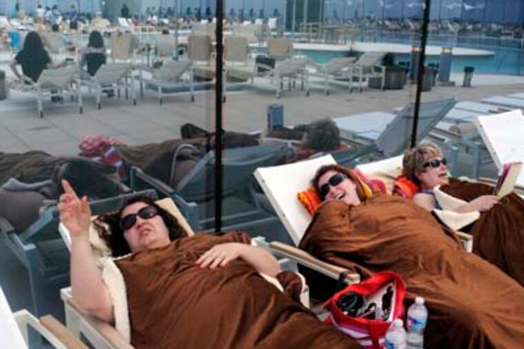 From left, Maria Markakis (cq), Sandi Syglowsi (cq) and her mother Joan Syglowsi (cq) all of Springfield, Delaware Co. keep warm by the In and Out Pool at the Revel during Grand Opening May 25, 2012. They were cold with the sea breezes and the hotel staff brought them the blankets. "They've been catering to us since we got here," said Maria. All of the Revel's restaurants, most of its 1,800 hotel rooms and 10 pools open for the Memorial Day weekend. ( TOM GRALISH / Staff Photographer )