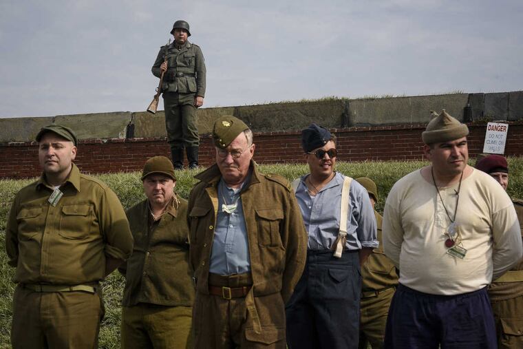 A reenactor in German uniform stands guard over others portraying POWs during a reenactment of a World War II prison camp at Fort Mifflin in Philadelphia on Saturday.