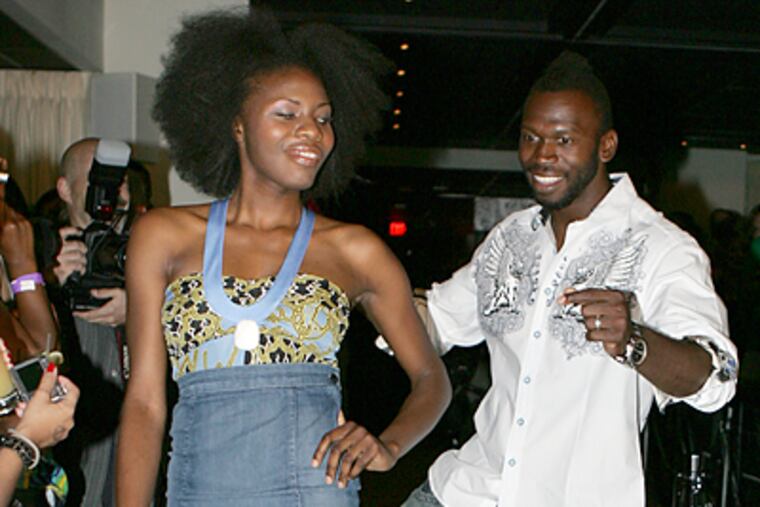 Eagles wide receiver Reggie Brown passes model Amala Enigive on the runway during the Rip the Runway Philly Style fashion show. (Barbara L. Johnston/Inquirer)