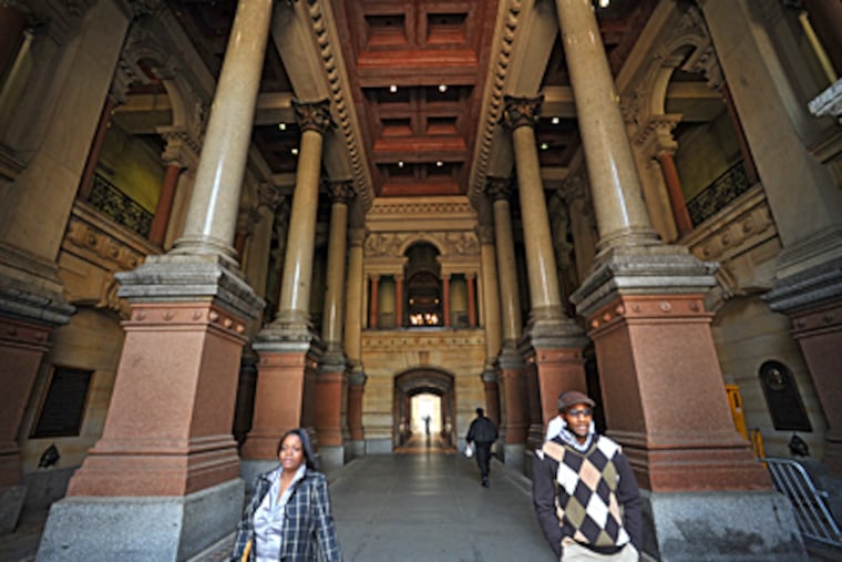 Pedestrians walk through the north portico of City Hall, with its marble columns and elaborate statuary. (Photo by Clem Murray / Inquirer)