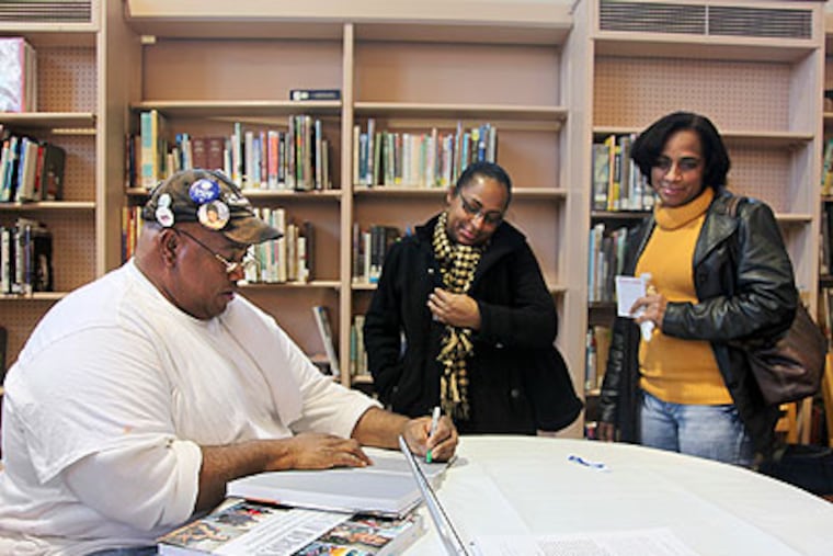 Ray Gant (left) signs copies of "Everyday Heroes: 50 Americans Changing the World One Nonprofit at a Time" for Keila Guerrero (center) and Noemi Bustamante (right) at McPherson Library in Kensington (Ryan S. Greenberg / Staff Photographer)