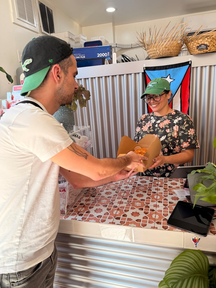 Brian Mattera picks ups pastelillos from Amaryllis Rivera-Nassar.