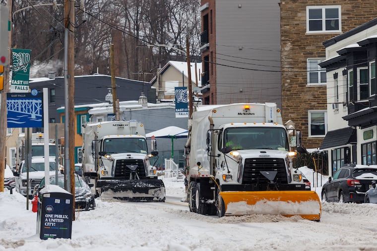 Sanitation Department trash trucks with plows clear snow during last month's storm.