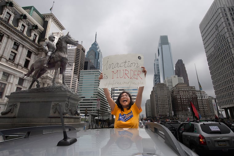 A woman appears out of the sunroof of her car as part of a protest to demand that Philadelphia and Pennsylvania officials reduce the population of jails, prisons, and detention centers in response to the COVID-19 outbreak.