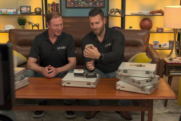 King of Collectibles: The Goldin Touch. (L to R) Ken Goldin (left) appraises trading cards with a staff member in an episode of the Netflix series "King of Collectibles: The Goldin Touch."