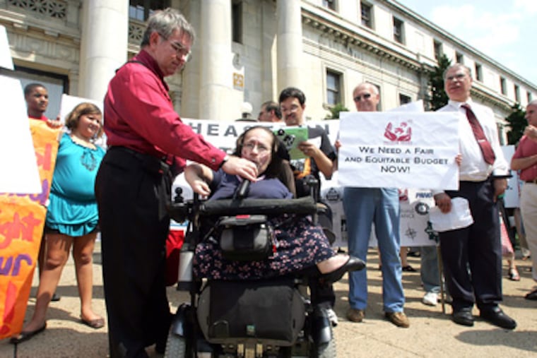 Michael Burke holds a microphone for Ann Cope, head of the Freedom Valley Disability Center, at the rally in Media. (David Swanson / Staff Photographer)