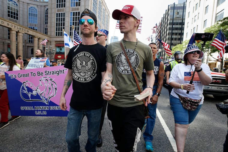 Peter Brown, center left, and Mark Hutt, center right, who said they are engaged to be married, hold hands as they march with others in the Straight Pride Parade in Boston, Saturday, Aug. 31, 2019.