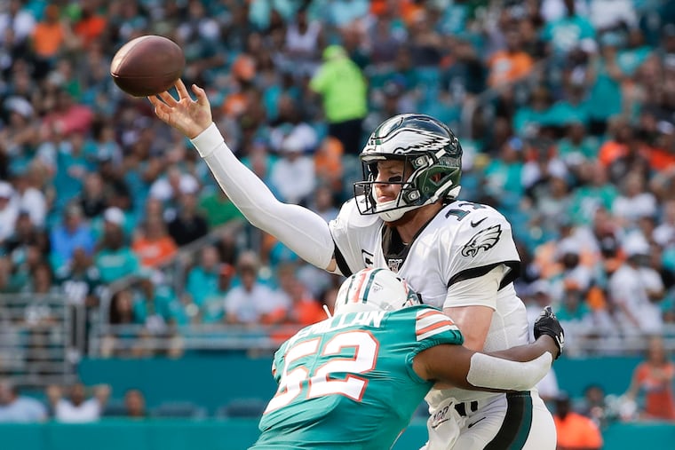 Eagles quarterback Carson Wentz gets rid of the football as he absorbs a hit from Dolphins linebacker Raekwon McMillan.