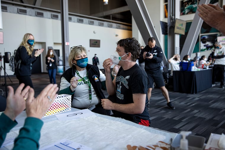 Trey Gillece, 20, is applauded by family and staff after receiving a COVID-19 vaccine at Lincoln Financial Field. Trey was nervous about the shot, but his father, Jim Gillece, held his hand and reassured him to be brave. "I do miss seeing everyone and talking to everyone. It’s been forever,” Trey said.