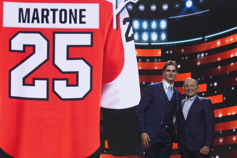 Porter Martone, second from right, stands next to NHL commissioner Gary Bettman after being drafted by the Philadelphia Flyers during the NHL hockey draft Friday, June 27, 2025, in Los Angeles. (AP Photo/Damian Dovarganes)