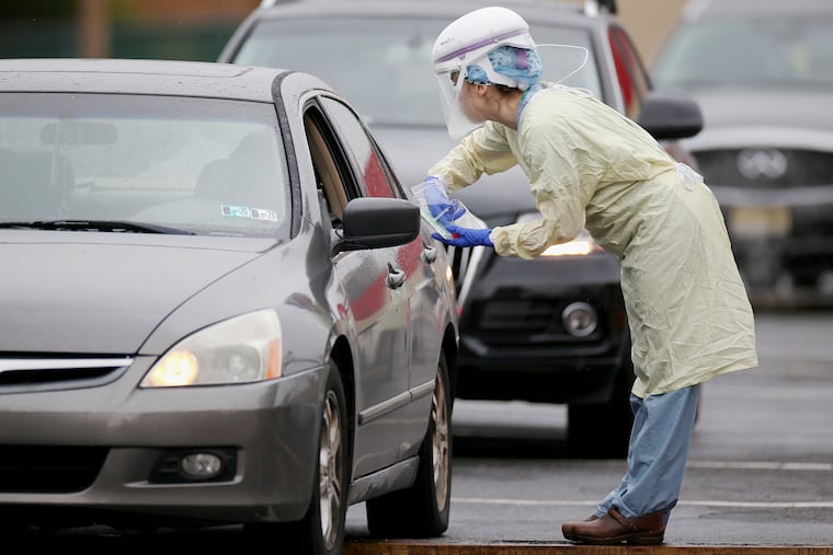 A medical worker collects samples from individuals who signed up for "drive-through testing" for the coronavirus at a Penn Medicine site in West Philadelphia on Tuesday, March 17, 2020. Penn, Jefferson and other area hospital systems have set up drive-through stations to swab for samples that can be tested for the coronavirus.