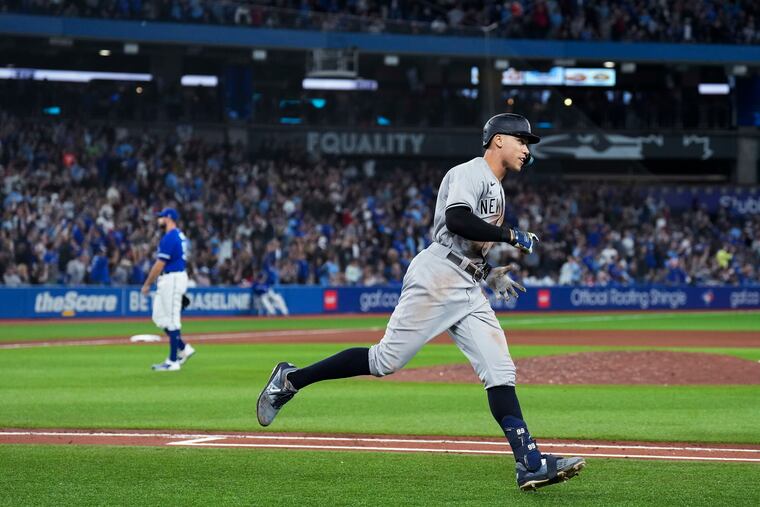 Aaron Judge runs the bases after hitting his 61st home run, off Toronto Blue Jays pitcher Tim Mayza, left.