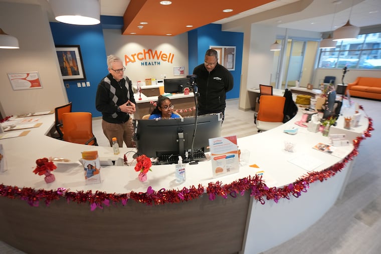 Doron Schneider, left, the medical director for Archwell Health in Philadelphia, looks over the shoulder a care navigator at the reception desk at Archwell's new clinic in Germantown.
