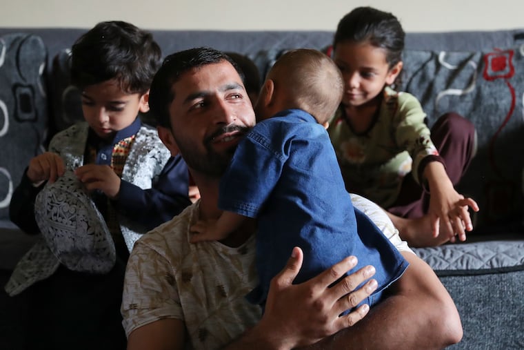 Mohammad Sabour Khalil holds his son while he speaks about access to healthcare in the living room of Mohammad Sadiq Sadeed’s Northeast Philadelphia home on Sept. 9. Khalil recently arrived from Afghanistan with his family in early August.