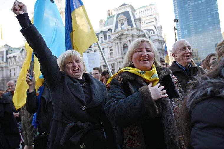 Halyna Kaspshyshak raises a fist during the singing of the Ukrainian national anthem at Sunday's gathering of about 200 people at Thomas Paine Plaza near City Hall.