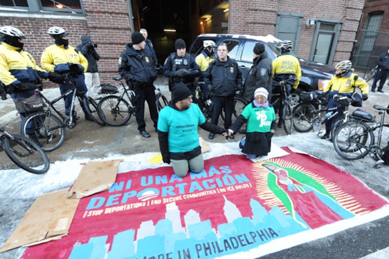 Miguel Serna (left) and his mother Maria, members of a groups called Juntos, hold hands in front of a cordon of police officers as they sit in front of the garage door for the US Citizenship and Immigration office in the 1600 block of Callowhill St. They and the group were protesting the lack of action on immigration reform in Washington and they were trying to block the ICE vans taking immigrant detainees to prison in York where deportation proceedings are processed. (CLEM MURRAY/Staff Photographer)