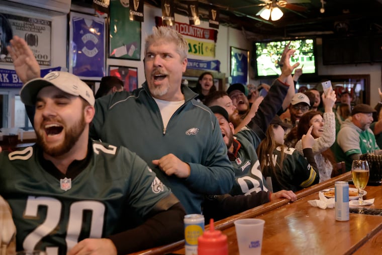 Sean Iaquinto of Hoboken (standing, second from left) and other members of the Philadelphia Eagles Club of Hoboken cheer at Mulligan's Pub in Hoboken, N.J., while watching the Eagles play the New Orleans Saints on Nov. 21, 2021.