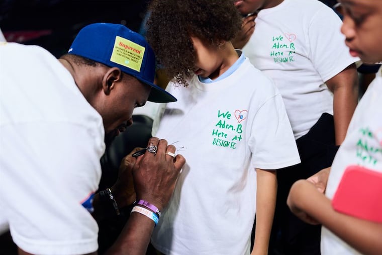 Adem Bona signing autographs for students from Design FC.