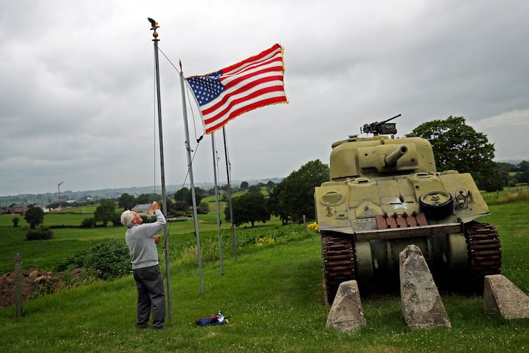 In this July 2020 photo, Marcel Schmetz raised the U.S. flag next to a WWII American Sherman tank at his Remember Museum 39-45 in Thimister-Clermont, Belgium.