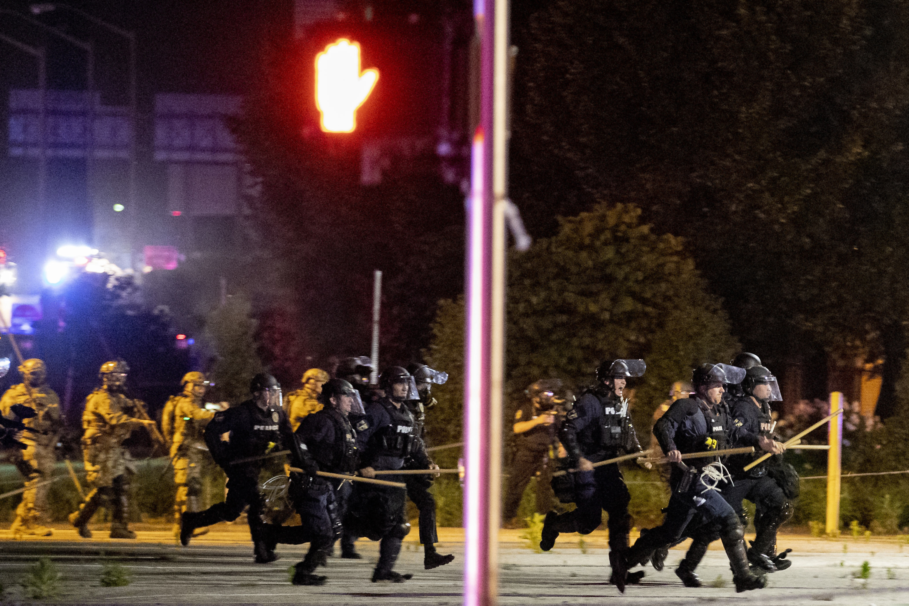 Police and Kentucky National Guard troops chasing protesters as they fled toward a fence Sunday.