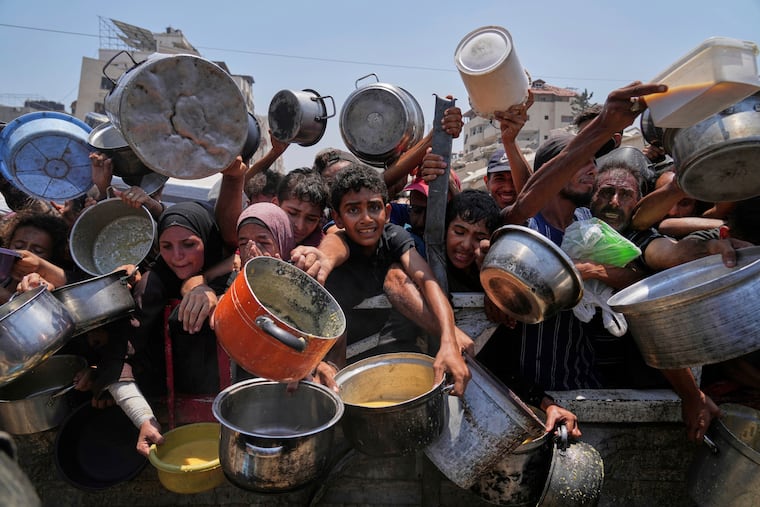 Palestinians struggle to get donated food at a community kitchen in Gaza City on July 26, 2025.