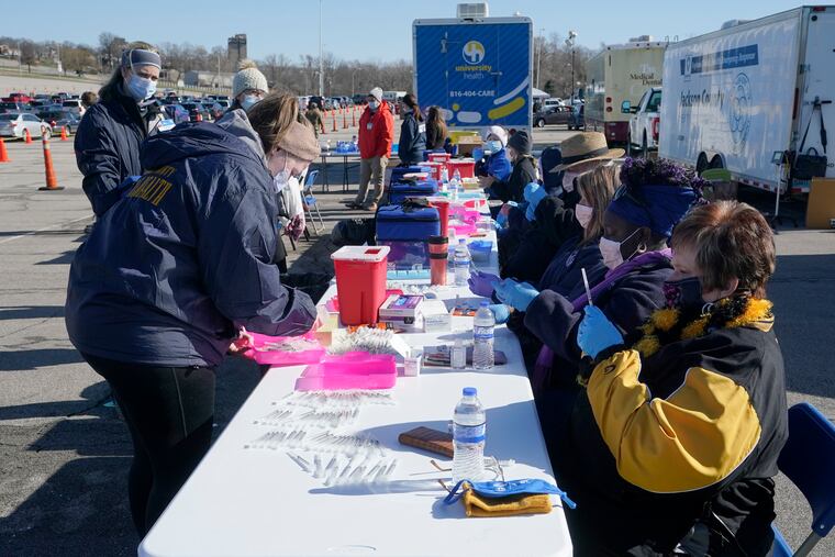 In this March 19 photo, nurses filled syringes with a COVID-19 vaccine at a mass vaccination site in Kansas City, Mo.