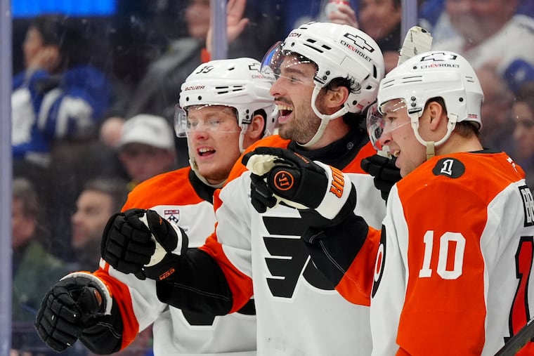 Flyers' Noah Cates (center) celebrates his third period goal with Matvei Michkov (left) and Bobby Brink.