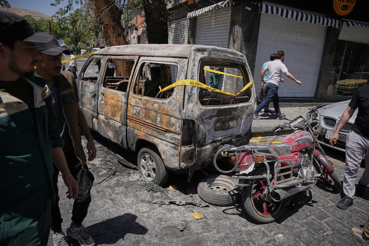 Syrian security personnel inspect a burned vehicles near the Four Seasons Hotel after two explosions rocked the area earlier while Syrian President Ahmad al-Sharaa was meeting French President Emmanuel Macron at the presidential palace, in Damascus, Syria, Tuesday, July 7, 2026.
