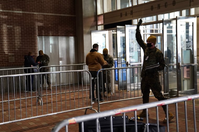 Soldiers check IDs of people as they arrive on the first day of the FEMA COVID-19 vaccination site at the Pennsylvania Convention Center in Center City Philadelphia on Wednesday, March 3, 2021.