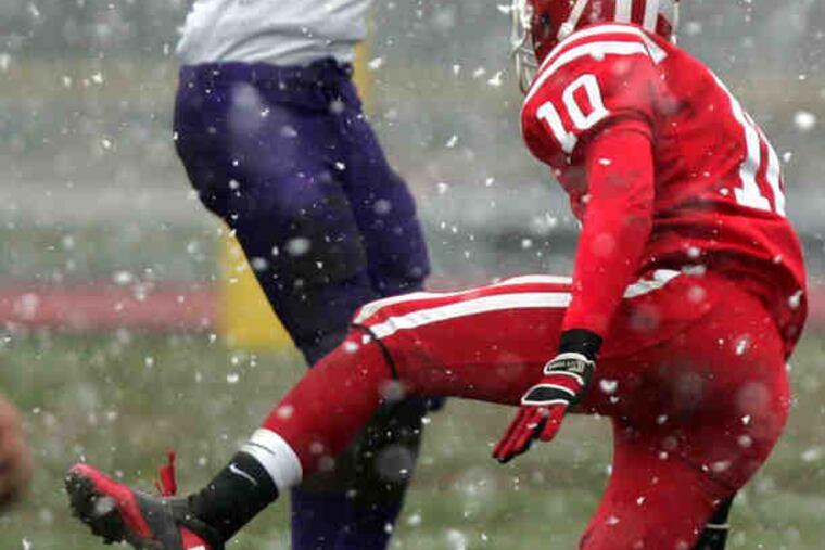 Terrell Lee of Cherry Hill West leaps for a first-down catch in front of Cherry Hill East's Taj Frazier. The Lions beat their rivals for the fourth consecutive year to keep the Al DiBart Memorial Trophy, known as "The Boot." "This is something we'll remember for the rest of our lives," said West senior Terrell Williams, who rushed 22 times for 93 yards. At right, East's Alex Weber punts in the snow.