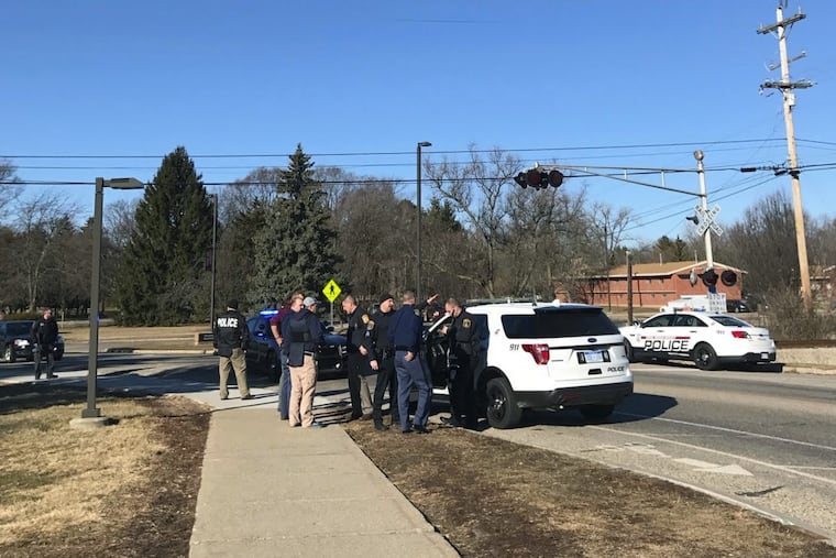 Authorities stand on the campus of Central Michigan University during a search for a suspect, in Mount Pleasant, Mich. School officials say police responded to a report of shots fired at a residence hall.