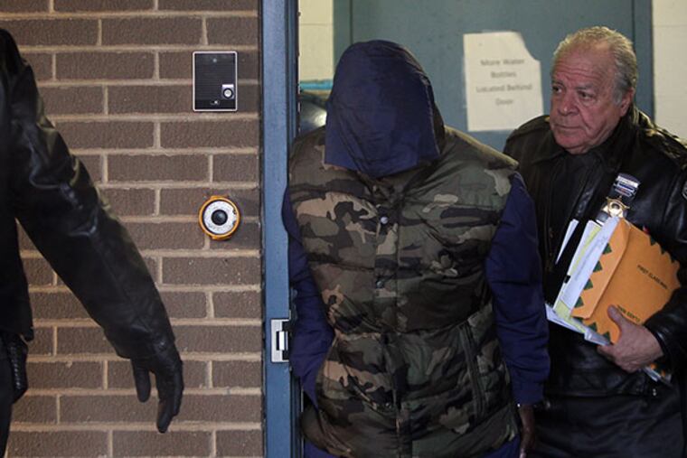 Upper Darby Police have arrested 58-year-old Ernest Marks and charged him in the in the hit-and-run death of Richard Patterson and his dog earlier this week. Police Superintendent Michael J. Chitwood said Ernest Marks had a history of driving with a suspended license and should not have been behind the wheel of a vehicle when he allegedly struck and killed Patterson. Marks, at left, covers his face as he is led out of Upper Darby police station on January 8, 2014. ( DAVID MAIALETTI / Staff Photographer )